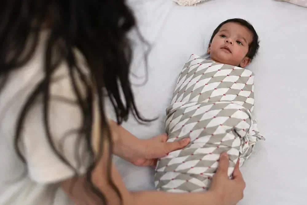 baby being wrapped in a swaddle to sleep