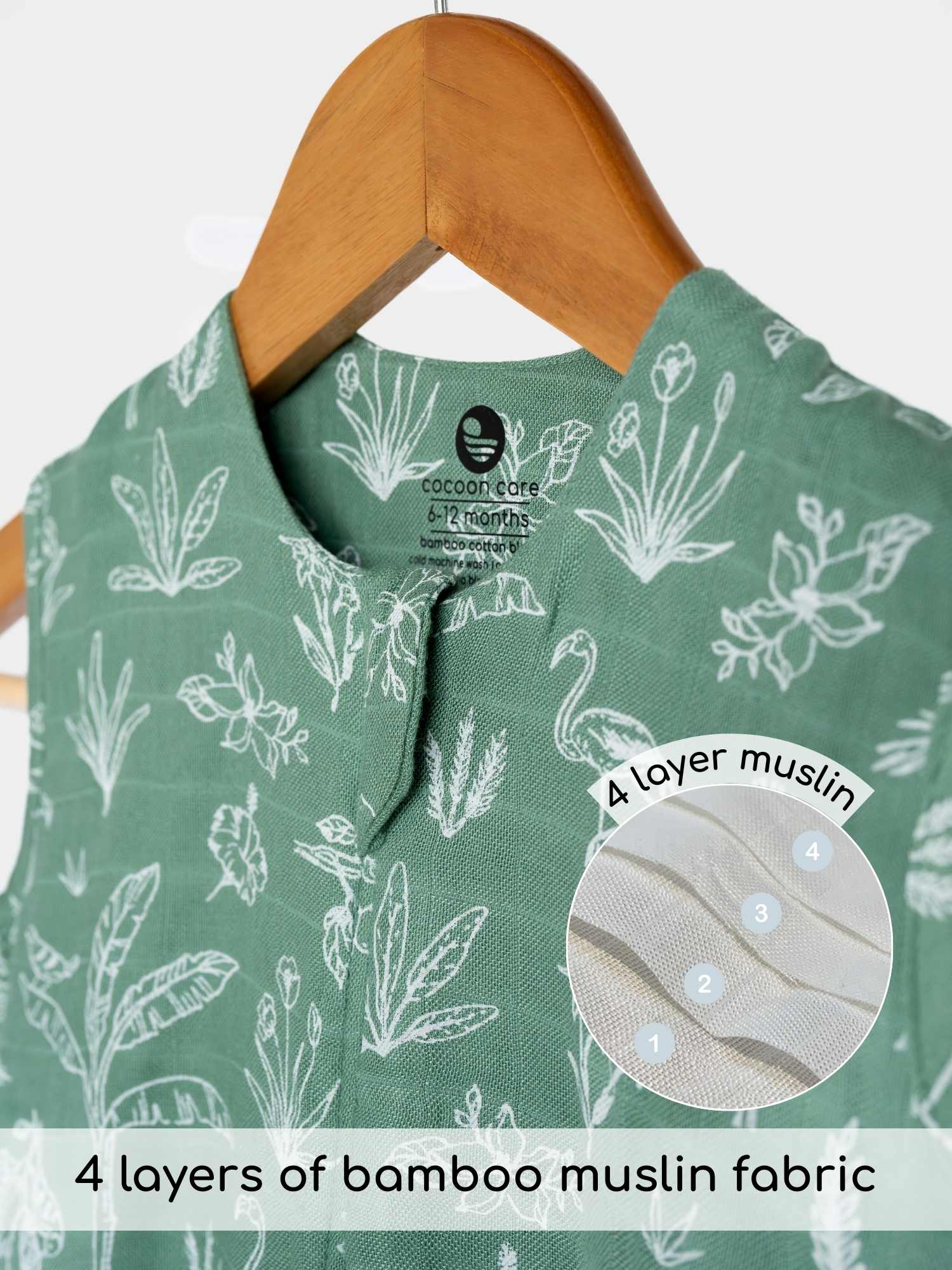 Green baby sleeping bag with floral pattern on a hanger, featuring bamboo muslin fabric details. cocoon care