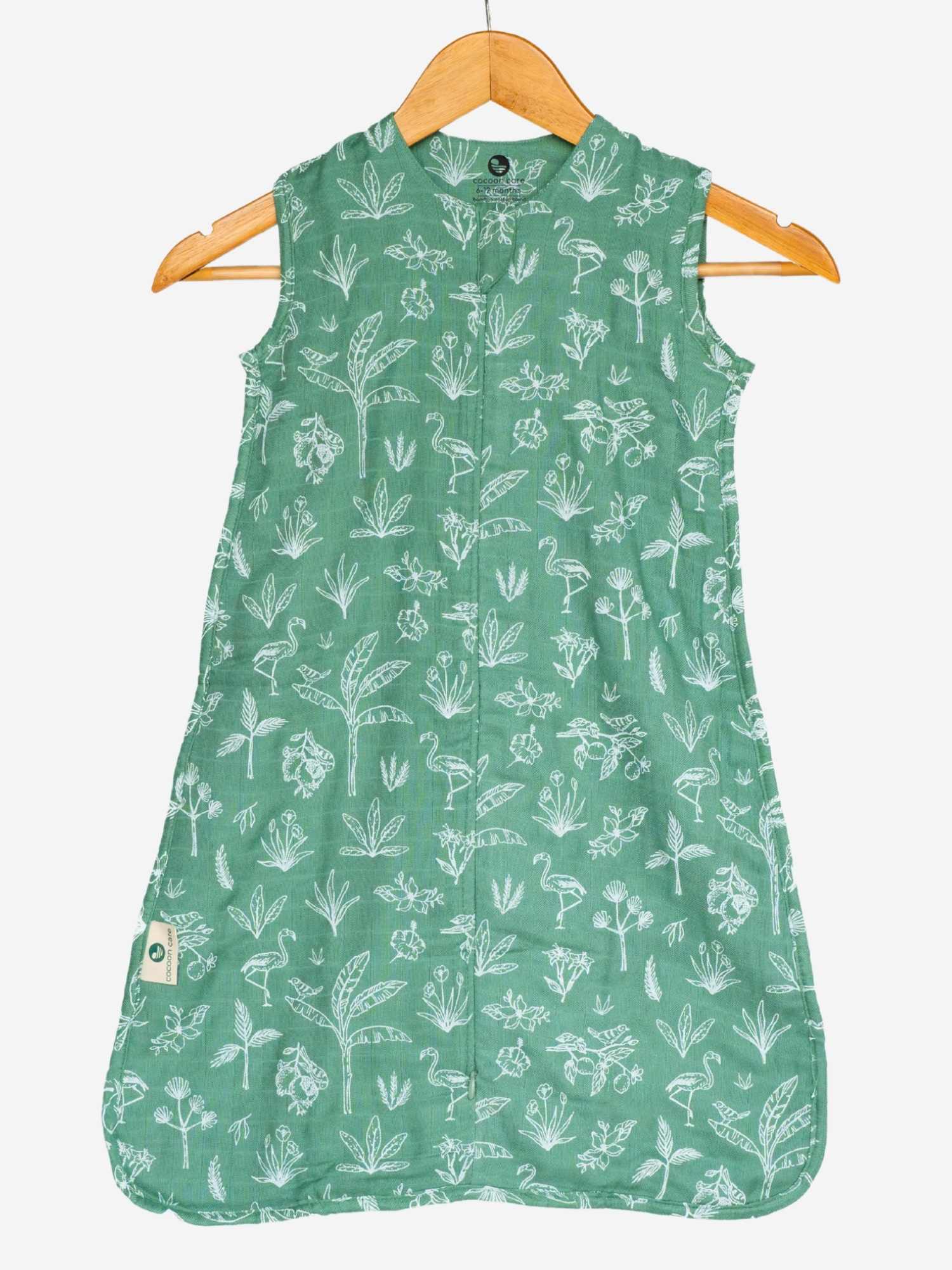 Green muslin sleeping bag with white floral pattern on a hanger against a white background cocoon care